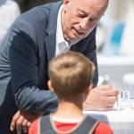 Minister Wolfgang Tiefensee spricht auf einen Stehtisch gelehnt mit einem Kin, dass einen Rucksack auf dem Rücken trägt.