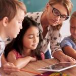 Lehrerin erklärt Kindern auf einem Tablet neue Dinge.