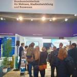 Das Foto zeigt einen Ausschnitt von einer Messe: mehrere Personen schauen zu einer vortragenden Person.