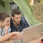 Ein Mann und eine Frau liegen in einem Zelt und schauen gemeinsam auf einen Laptop.