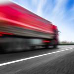 LKW der auf einer Straße fährt und durch seine Geschwindigkeit unscharf ist