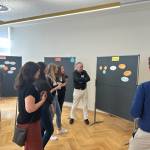 Mehrere Personen stehen vor einer Pinnwand mit Post Its.