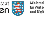 Links ein Schriftzug: "Freistaat Thüringen", in der Mitte das Wappen des Freistaats Thüringen (ein auf- recht stehender, achtfach rot-silbern gestreifter, goldgekrönter und goldbewehrter Löwe auf blauem Grund, umgeben von acht silbernen Sternen), Rechts daneben ein Schriftzug: "Ministerium für Wirtschaft, Wissenschaft und Digitale Verwaltung".