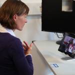 Frau sitzt vor Laptop und spricht darüber mit einer Ärztin.