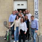 Teilnehmende stehen aufgereiht, auf und neben einer Treppe, vor einem Eingang, auf einem Schild steht: JEDI - Jena Digital Innovation Hub