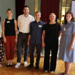 4 Frauen und 2 Männer stehen in einer Reihe und lächeln in die Kamera