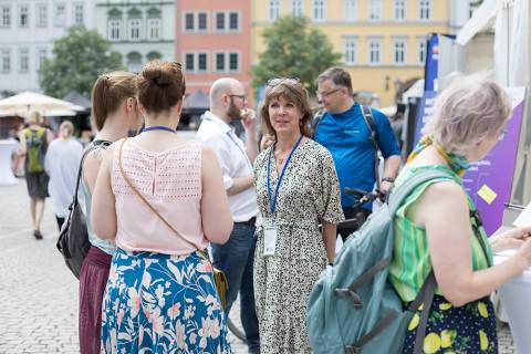 Die 5G Projektmanagerin Heike Stötzner im Gespräch mit der Gesamtleiterin Dorothea Prell und einer Bürgerin. Dazu sind weitere im Gespräch befindliche Menschen auf dem Bild.