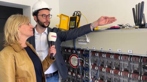 Ein Mann und eine Frau sind im Gespräch über das aktuelle 5G-Projekt in Jena. Rechts im Bild sind verschiedene Hebel und Schalter zu sehen.