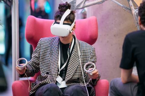 Eine Frau auf einem pinken Sessel mit einer VR-Brille auf