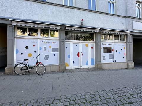 Foto von außen von dem ProbierLaden in Jena. Die Fenster sind bunt beklebt und davor steht ein Fahrrad.