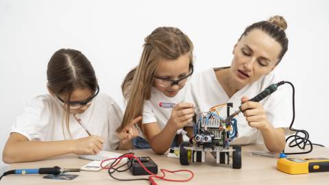 Mädchen und Lehrerin machen Wissenschaftsexperimente zusammen mit Roboterauto.