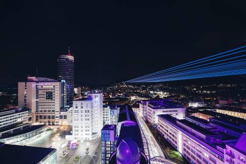 Jena bei Nacht mit vielen bunten leuchtenden Strahlen.