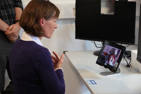 Frau sitzt vor Laptop und spricht darüber mit einer Ärztin.