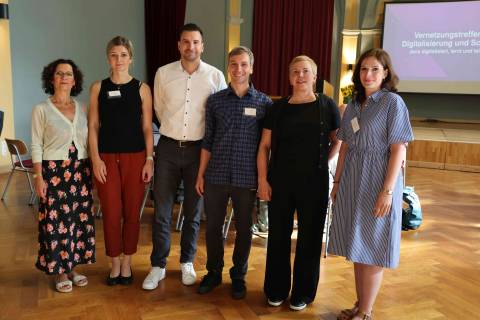 4 Frauen und 2 Männer stehen in einer Reihe und lächeln in die Kamera
