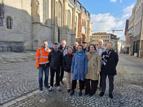 Viele Menschen schauen in eine Kamera.