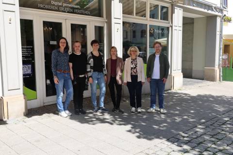 6 Personen ( v.l. Nicole Bergmann, Oliver Ephrosi Menchau, Anna Geißler, Sara Delinger-Parcetic, Dr. Angela Anding, Lokas Dorn) stehen vor einem Laden mit der Aufschrift "ProbierLaden - Digital gemeinsam. Probieren. Erleben. Verstehen." 
