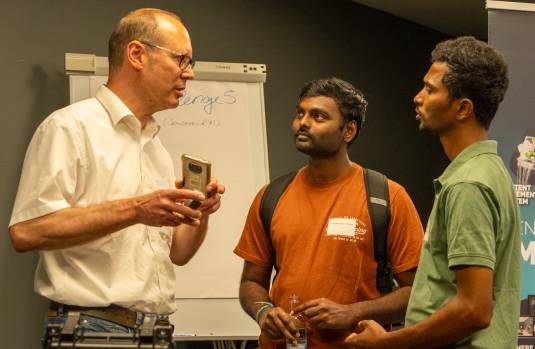 Drei Personen stehen in einem Raum und unterhalten sich.