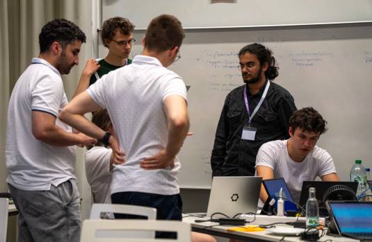 Mehrere Personen stehen in einem Kreis und disktutieren.