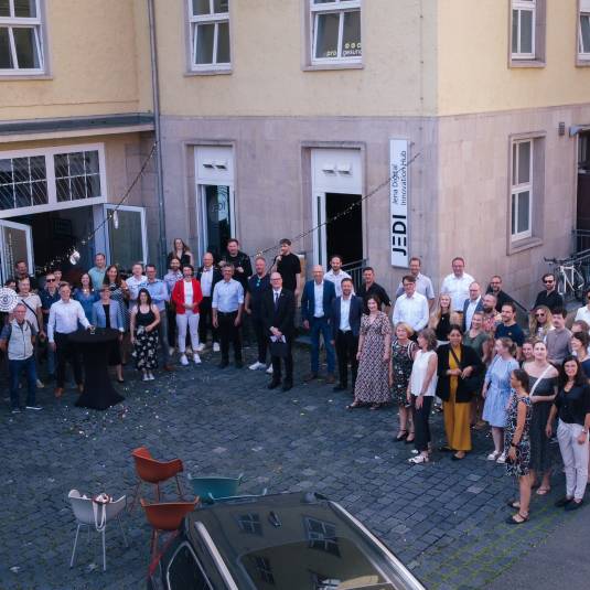 Viele Menschen stehen vor einem Gebäude und freuen sich.