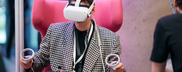 Eine Frau auf einem pinken Sessel mit einer VR-Brille auf
