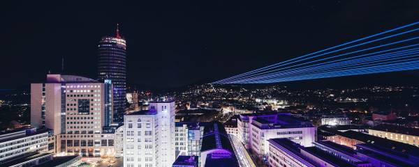 Jena bei Nacht mit vielen bunten leuchtenden Strahlen.