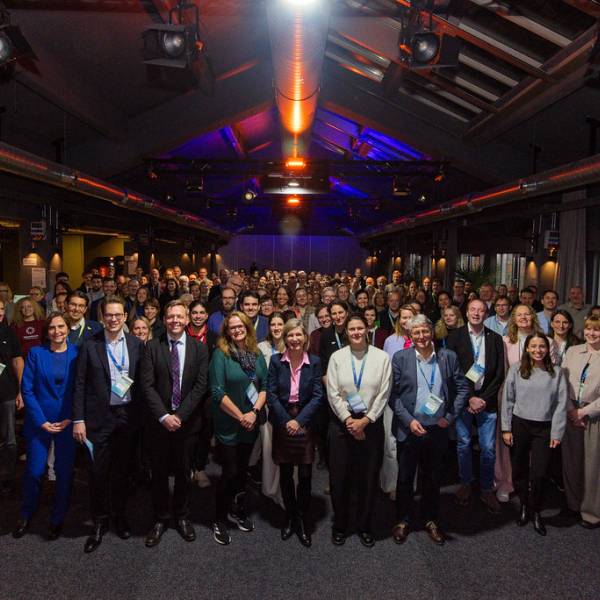 Ganz viele Menschen stehen in mehrerer Reihen neben- und hintereinander und schauen mit einem Lächeln in die Kamera