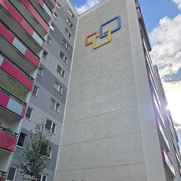 Mehrere Menschen stehen vor einem Hochhaus und schauen in die Kamera.