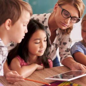 Lehrerin erklärt Kindern auf einem Tablet neue Dinge.