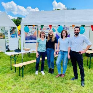 v.l.: Heike Stötzner, Vanessa Huber, Dorothea Prell und Dezernent Benjamin Koppe stehen vor dem Smart City Stand bei "Dein Tag im Paradies" 2024. . Im Hintergrund sieht man ein Zelt mit Plakaten des Projekts "5G-Verkehrsvernetznung" und "Smart City Projekt".