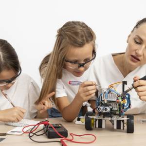 Mädchen und Lehrerin machen Wissenschaftsexperimente zusammen mit Roboterauto.