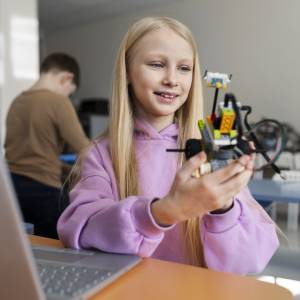 Schülerin hält selbstgebauten Roboter in der Hand.