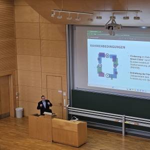 Mann steht am Podium und hält Vortrag in einem Uni-Hörsaal.