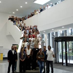 Gruppe von vielen Menschen stehen auf einer Treppe und lächeln in die Kamera.
