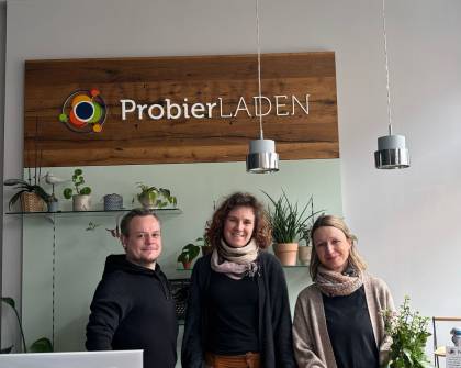 Das Team vom ProbierLaden steht am Empfangstresen und lächelt in die Kamera.